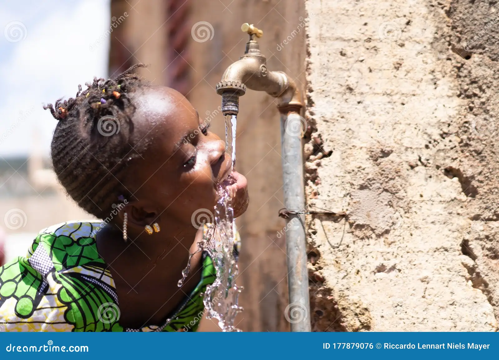 Un enfant boit de l'eau claire à un robinet. Illustration de l'accès à l'eau potable.